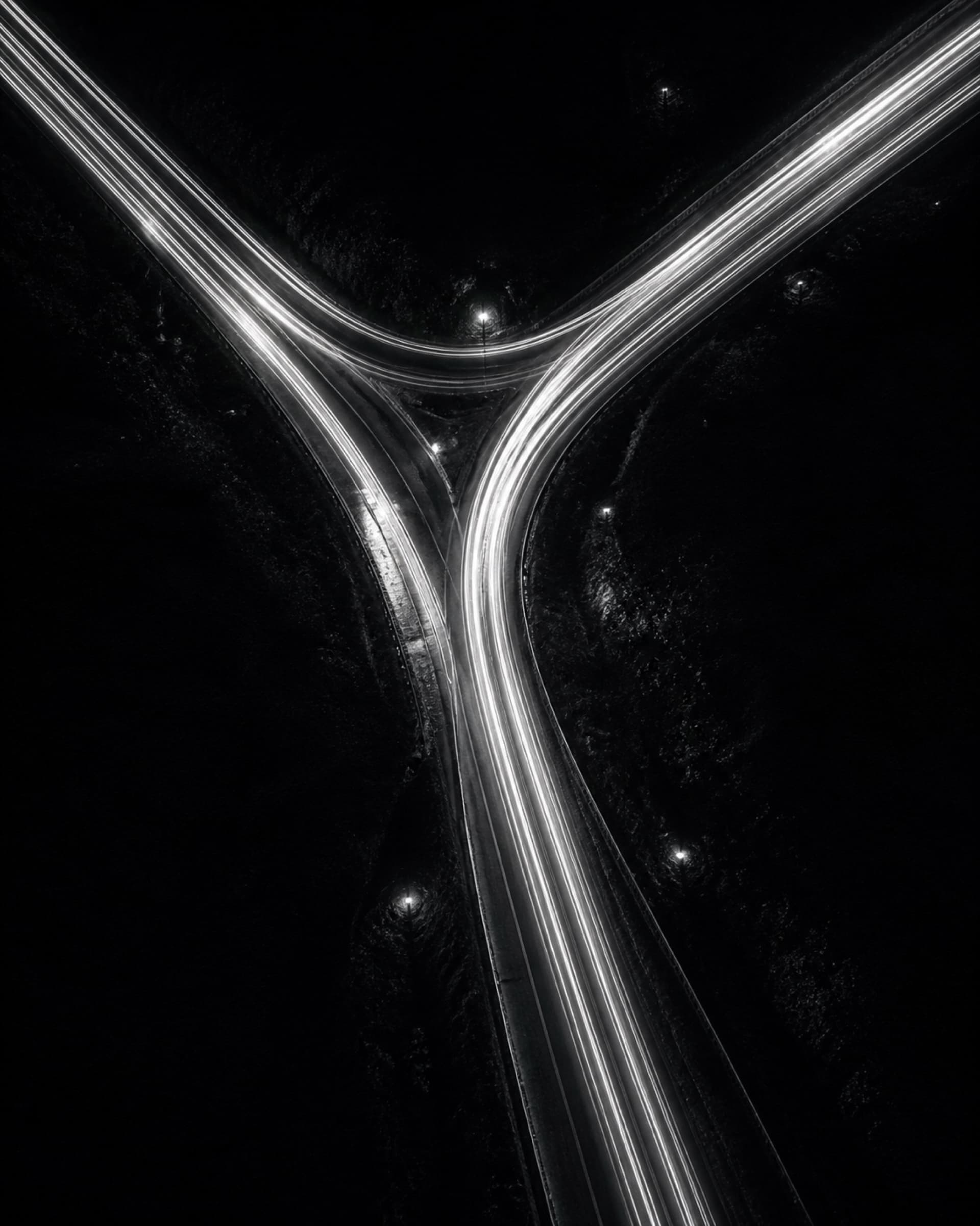 A long exposure of a road at night, with light trails through a junction.