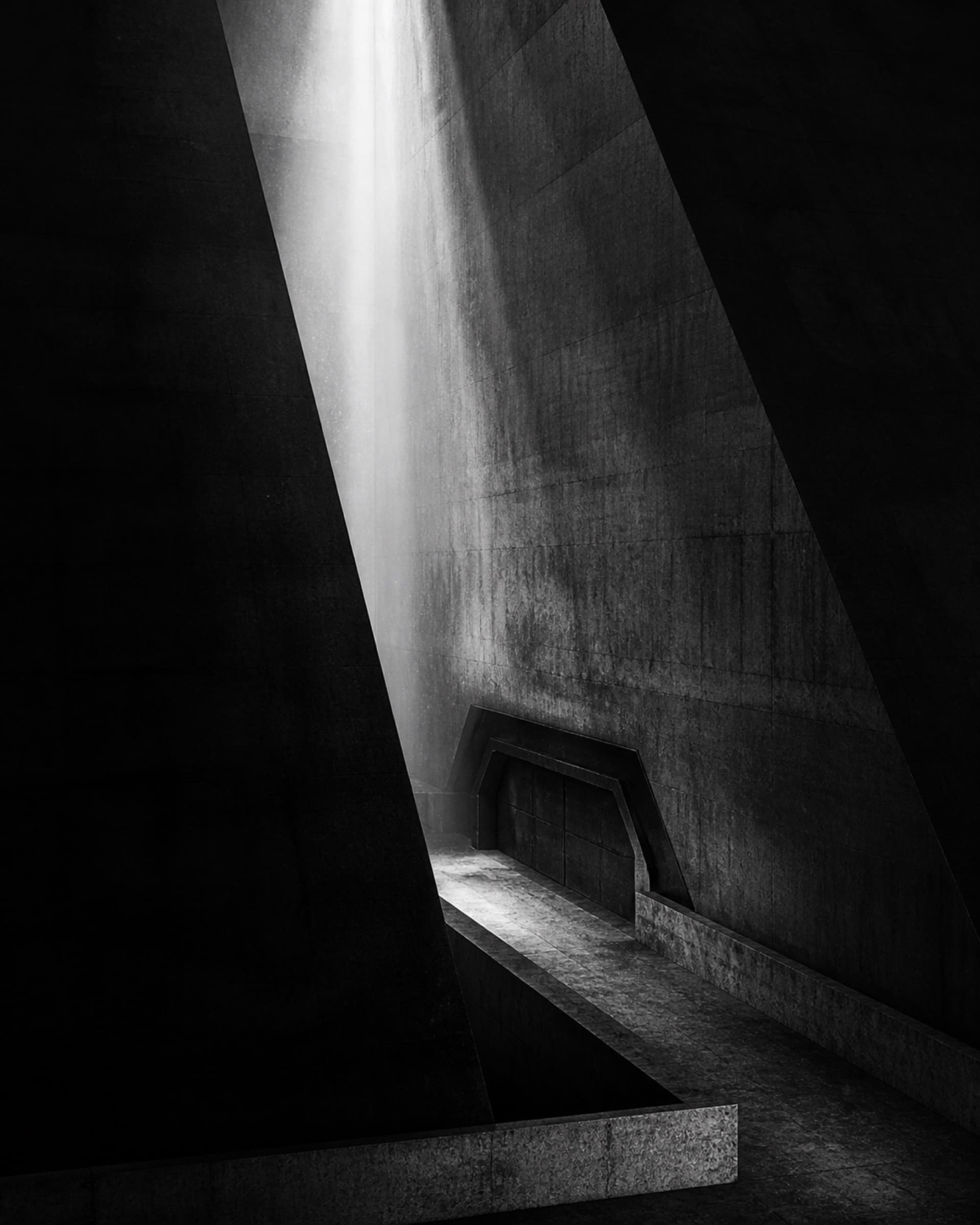 A monumental secure transition chamber cut by a shaft of white light.