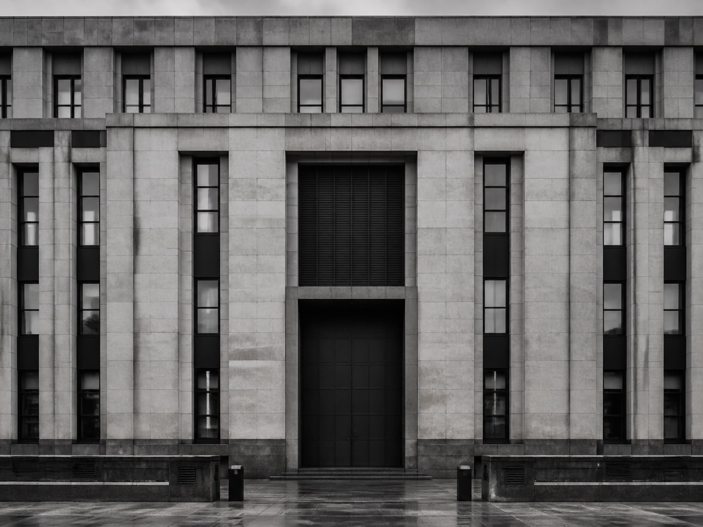 A civic building's stone facade in flat daylight, seen straight on.