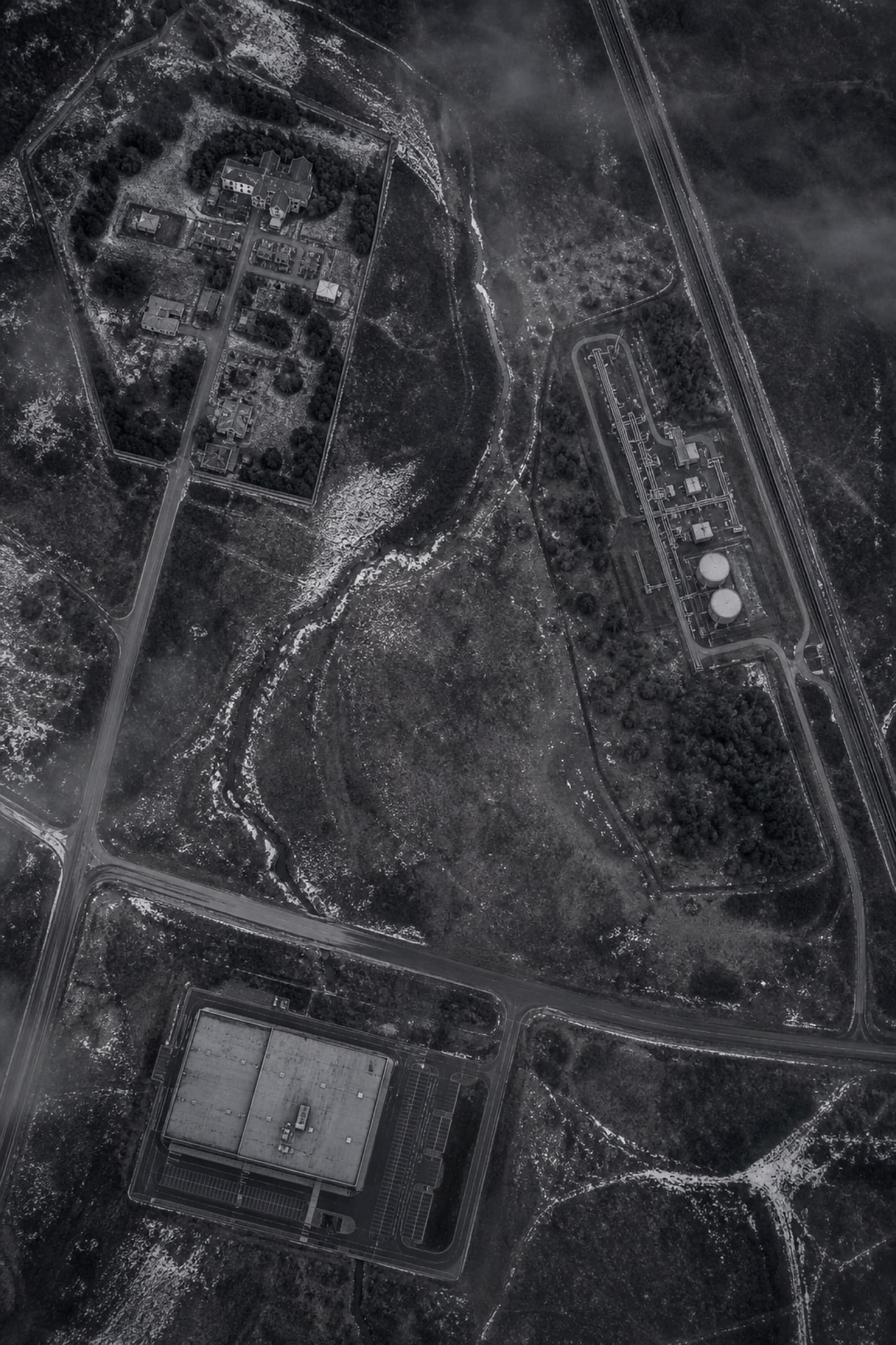 An aerial view of separate buildings and roads across open ground.